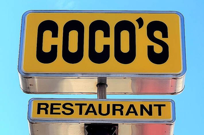 Sign reads “Coco’s Restaurant” against a clear sky