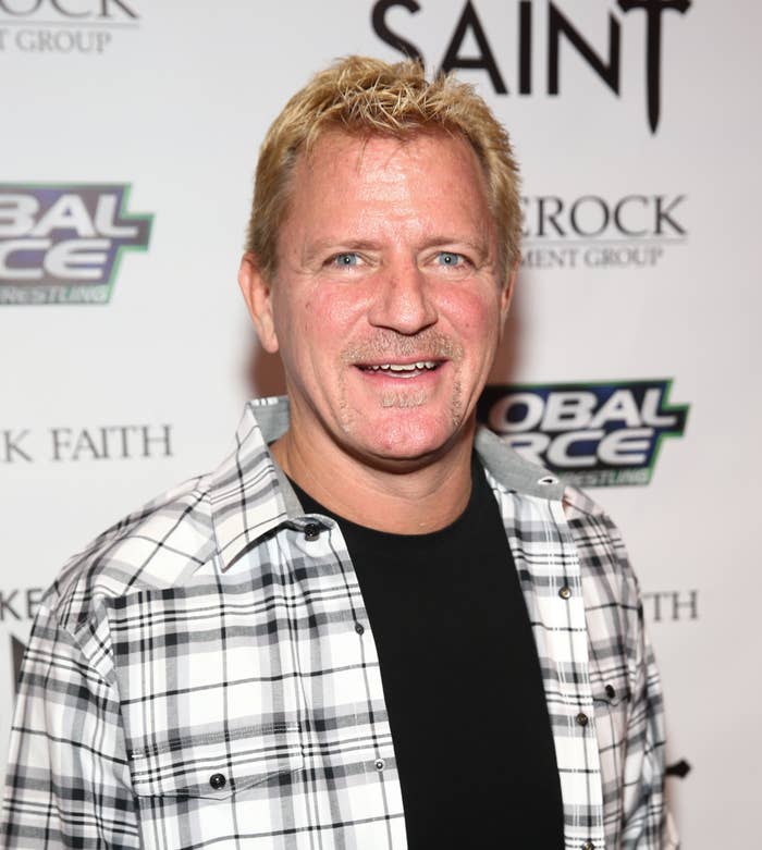 Jeff Jarrett wearing a casual black shirt under a plaid shirt, smiling on the red carpet at a Global Force Wrestling and The Masked Saint event