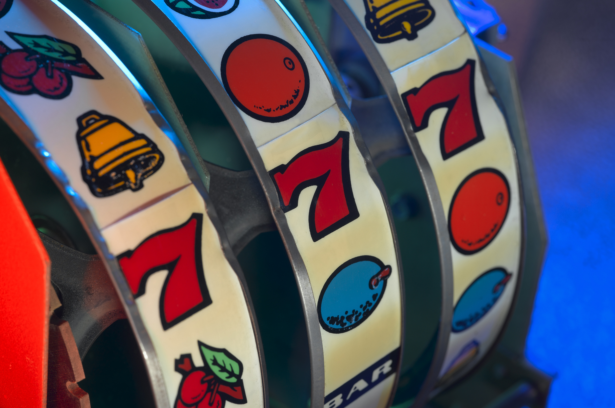 Close-up of a slot machine's spinning reels displaying a combination of symbols including cherries, a bell, and the number seven