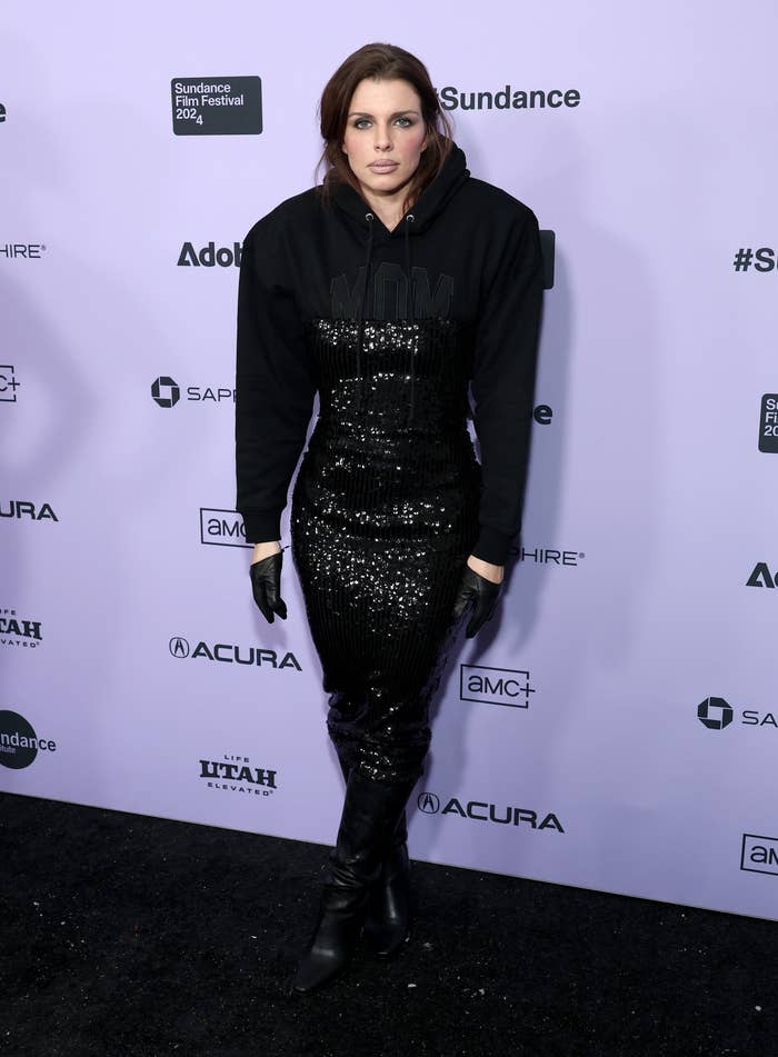 Julia Fox at Sundance Film Festival 2023, wearing a black sequin dress and a black hoodie with "WOMAN" written on it, along with black boots and gloves