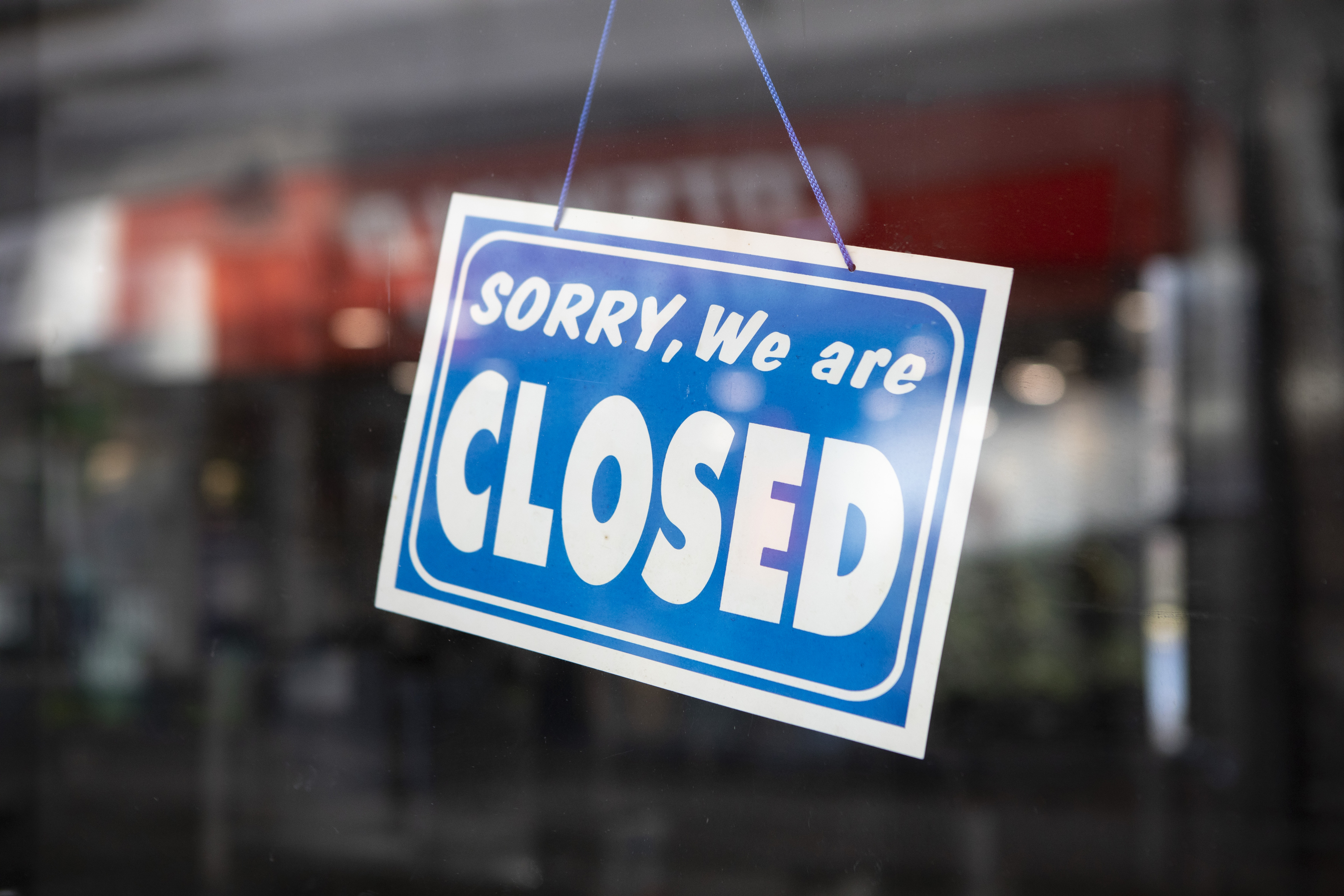A sign hangs on a shop door saying "SORRY, We are CLOSED."