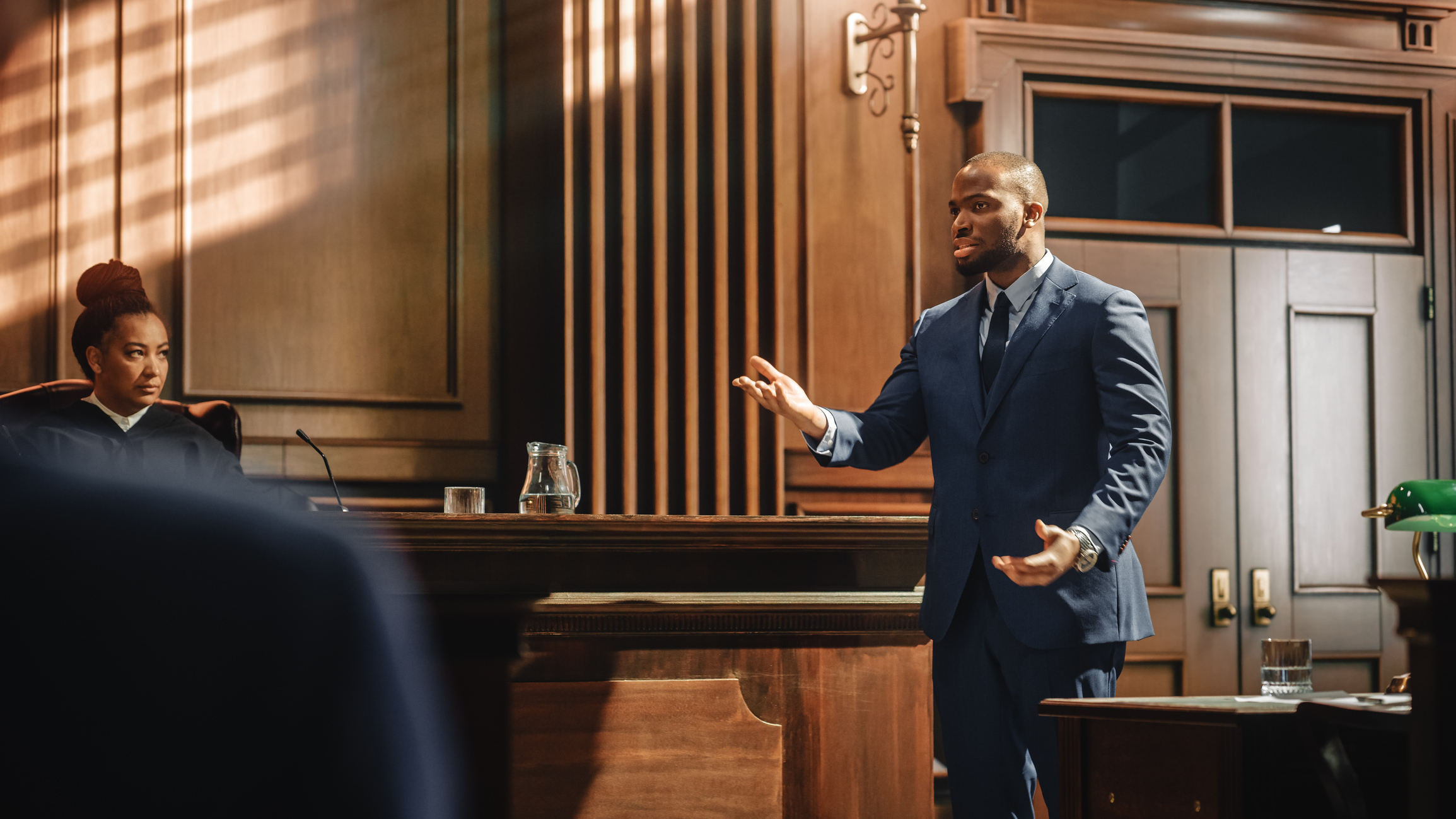 A lawyer passionately argues a case in a courtroom, while a judge listens attentively from the bench