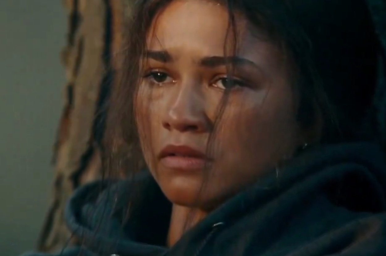 Zendaya looks emotional, wearing a hoodie and leaning against a tree, in an intense scene