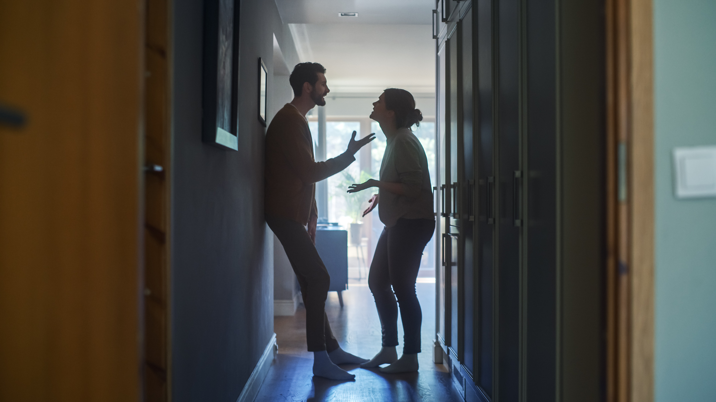 Man and woman silhouetted in a dimly lit hallway, seemingly engaged in a heated argument or discussion