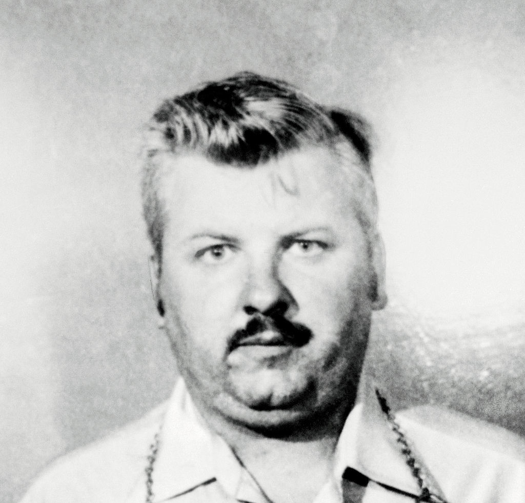 Black-and-white image of John Wayne Gacy with a neutral expression, wearing a collared shirt