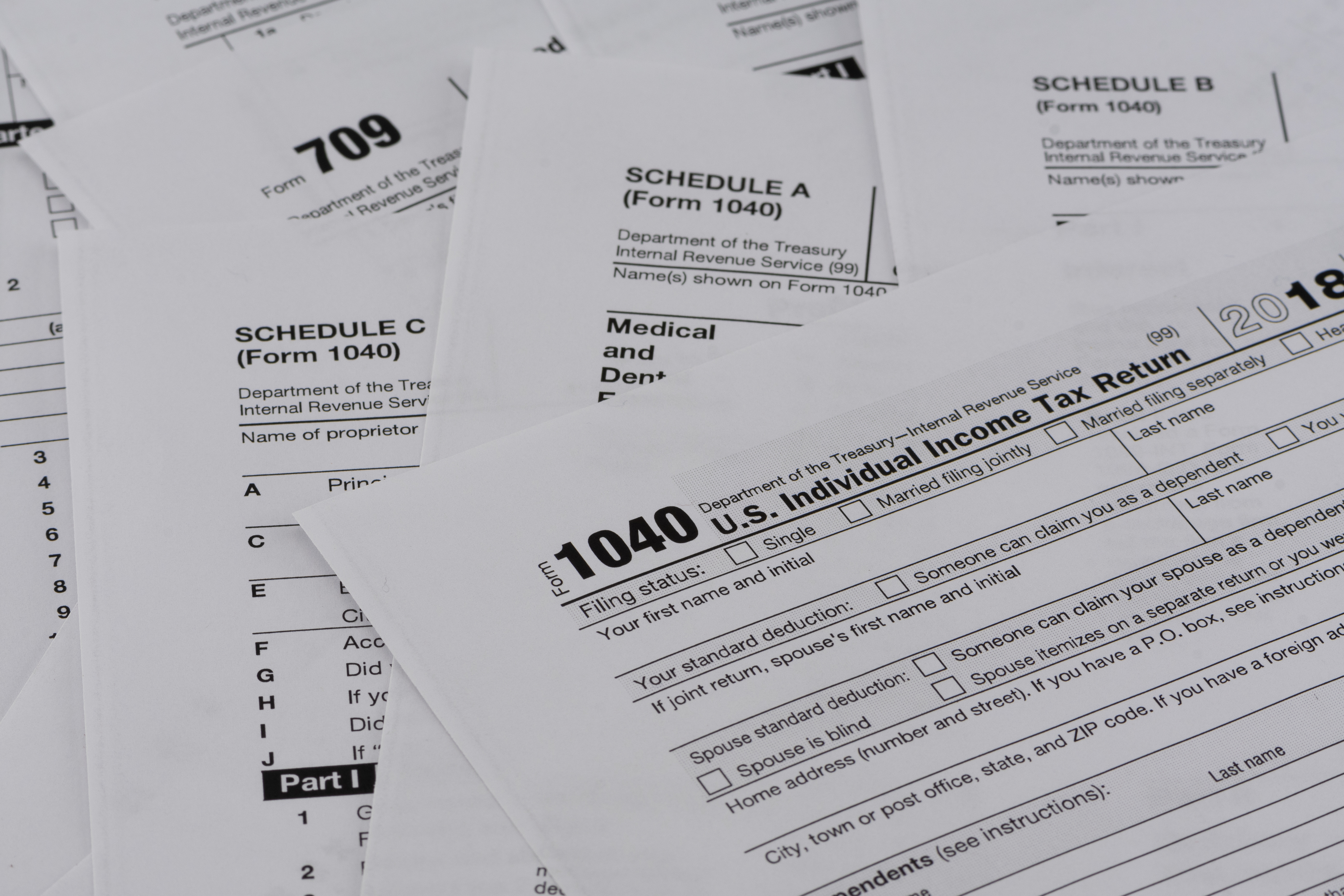 U.S. tax forms including Form 1040, Schedule A, and Form 709 scattered on a surface