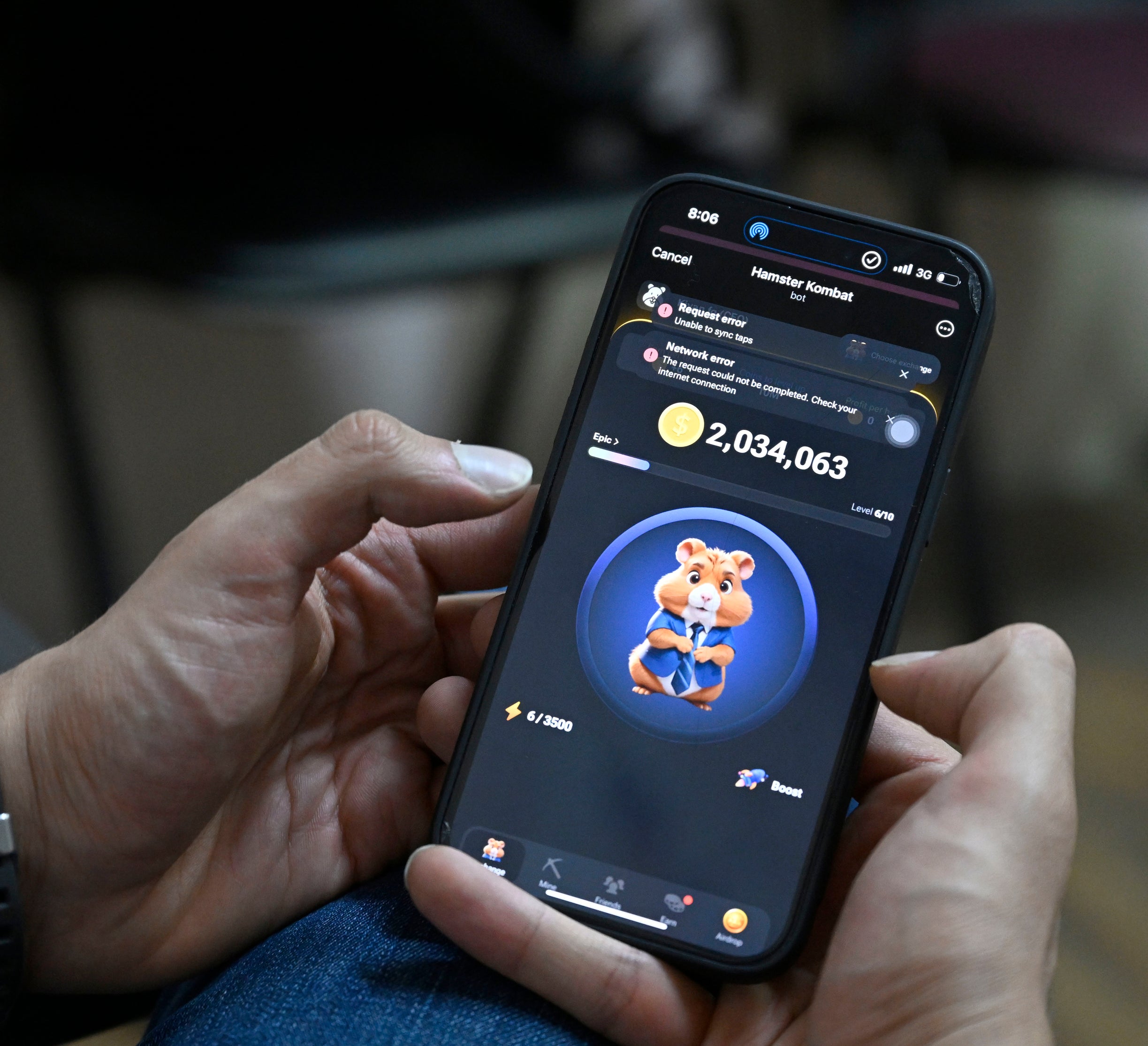 A person holds a smartphone showing a game with a cartoon mouse and the score of 2,034,063 on the screen