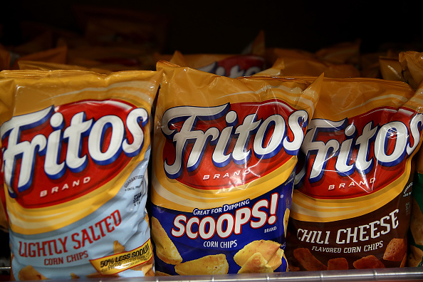 Three bags of Fritos corn chips on a shelf, with flavors: Lightly Salted, Scoops, and Chili Cheese
