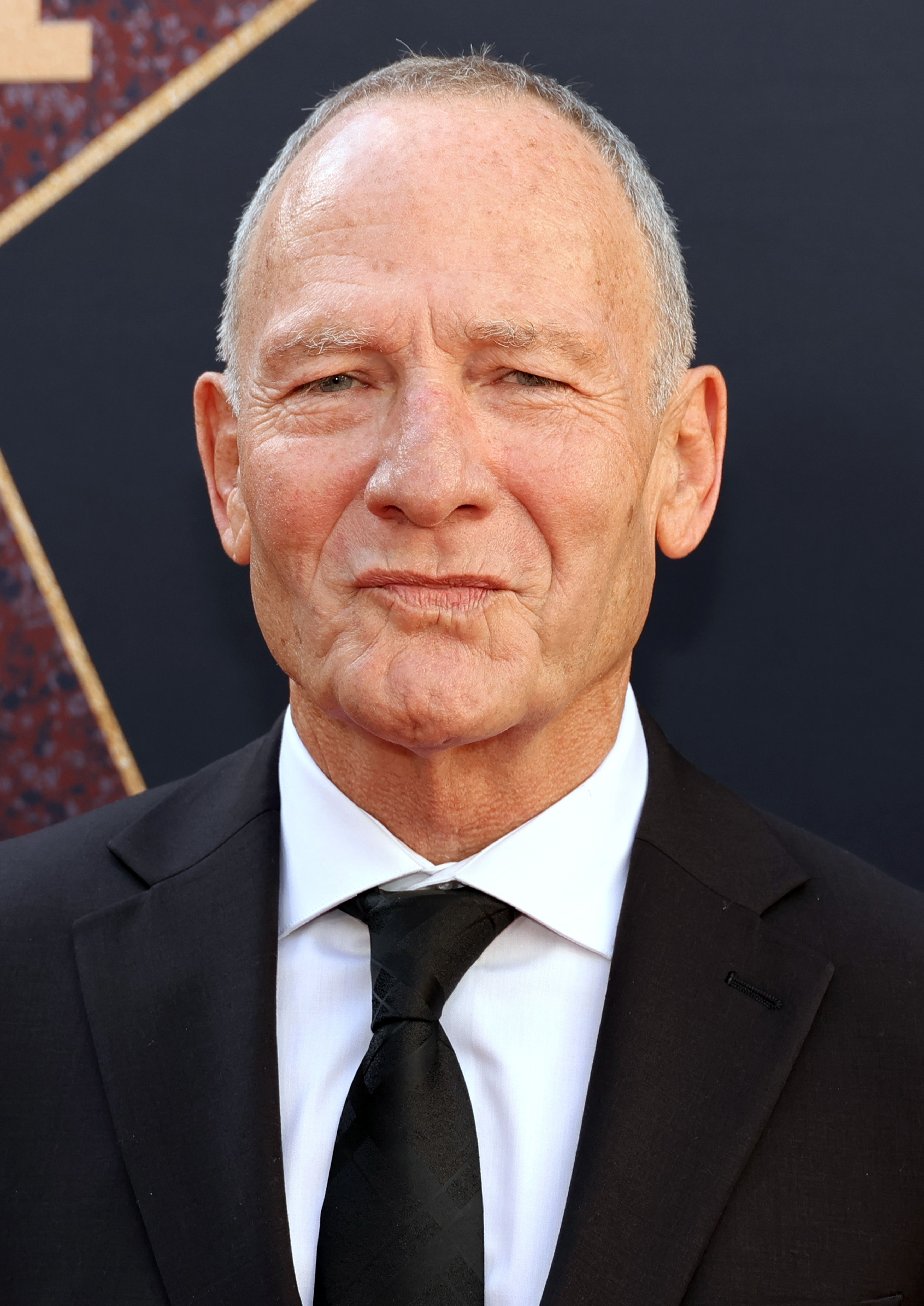 Simon Prast in a suit and tie at the premiere of "MaXXXine"