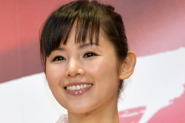 女優の上白石萌音がレースのディテールが特徴的なエレガントなドレスを着て、微笑んでいる。