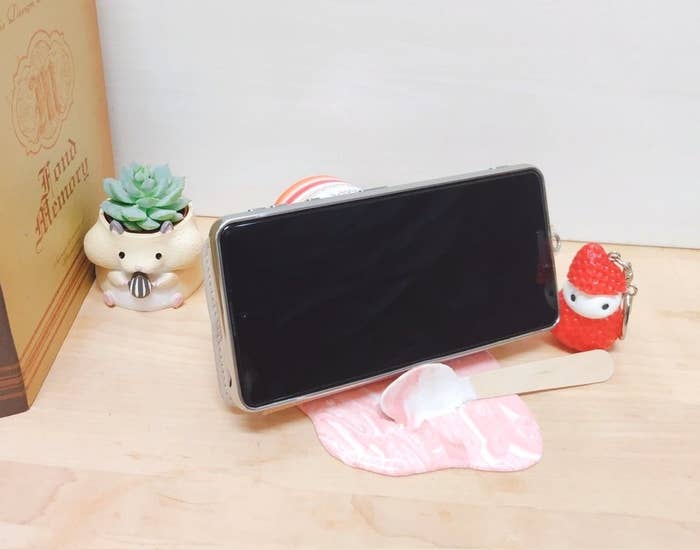 本とスマートフォンの横に多肉植物と2つの小さな人形が置かれている。