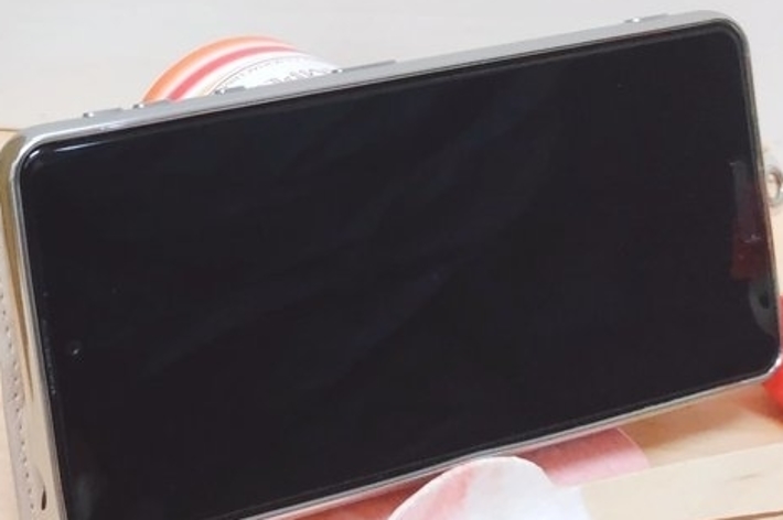 本とスマートフォンの横に多肉植物と2つの小さな人形が置かれている。