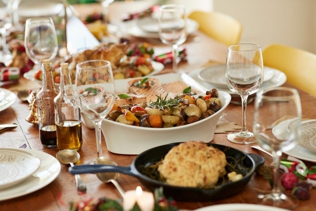 A table set for a festive meal, featuring various dishes like roasted vegetables, salad, and bread, with wine glasses and condiments