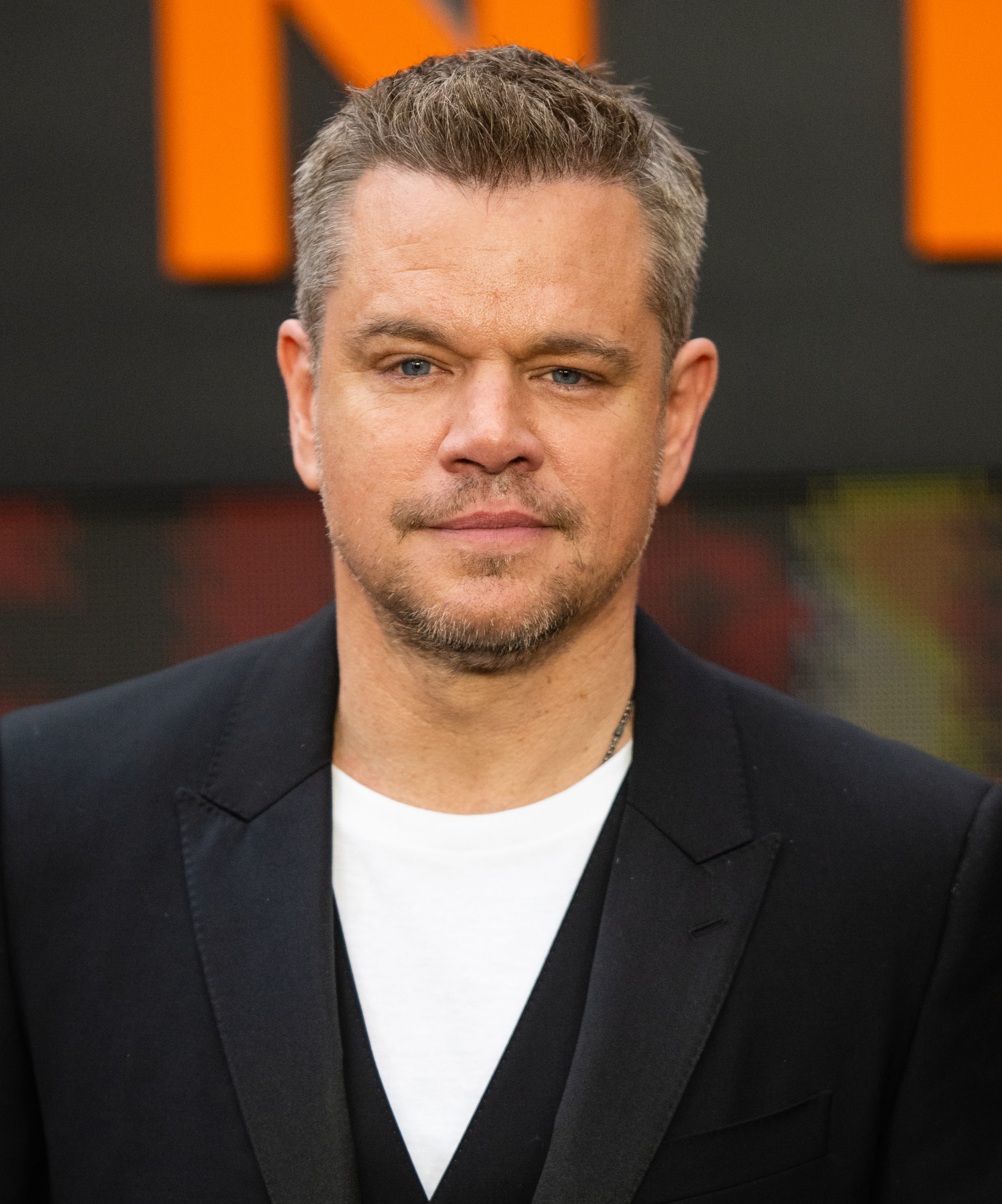 Matt Damon at a public event, wearing a casual white shirt under a black blazer