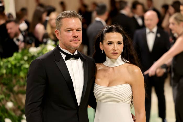 Matt Damon and Luciana Barroso pose together at a formal event, with Matt in a tuxedo and Luciana in a stylish white gown