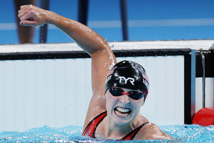 Katie Ledecky celebrates triumphantly in a swimming pool, wearing a swim cap and goggles