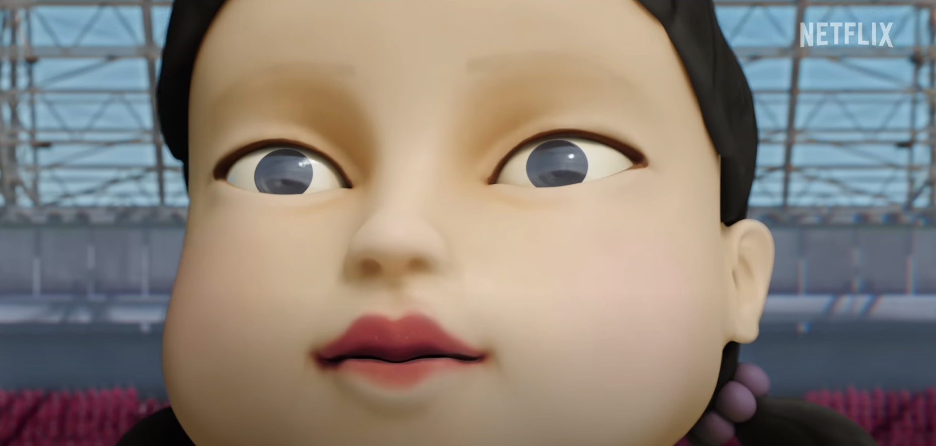 Close-up of the giant doll from Netflix's Squid Game, with a background of a large playing area