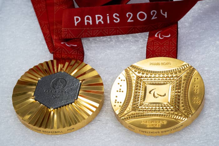 Two Paris 2024 Paralympic gold medals with red lanyards, featuring tactile designs to aid visually impaired athletes
