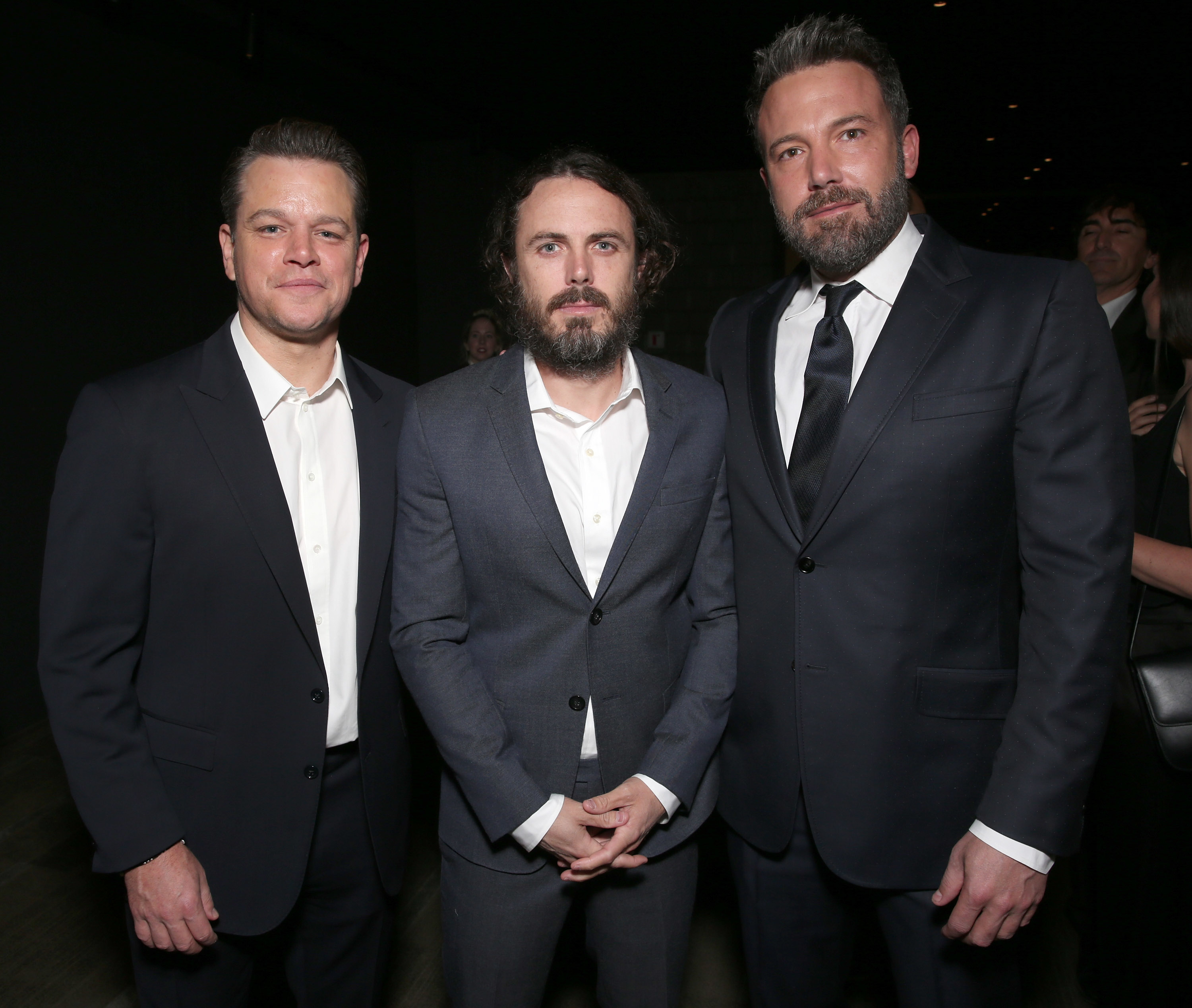 Matt Damon, Casey Affleck, and Ben Affleck in suits at a formal event