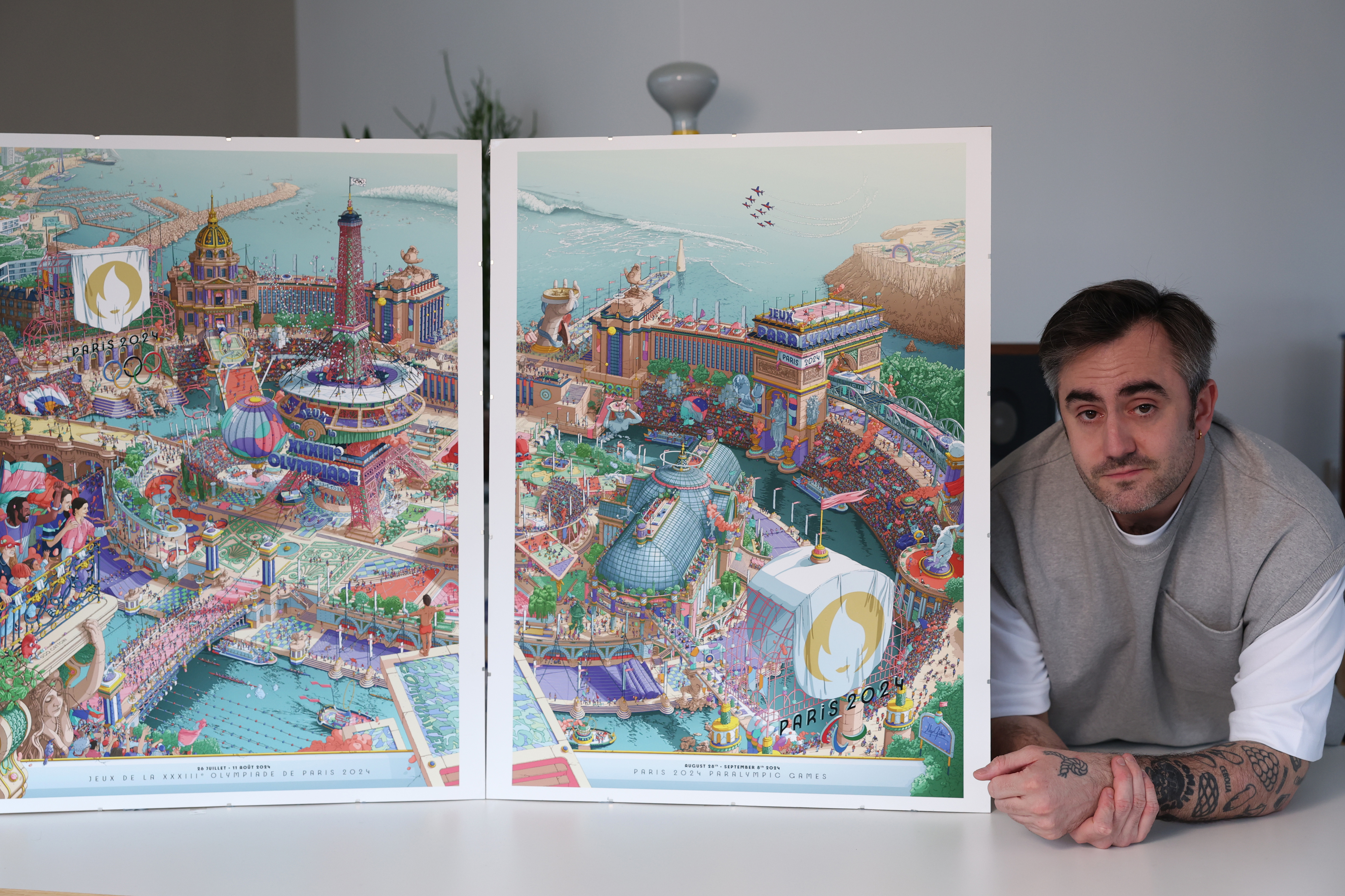 A man stands next to detailed posters depicting vibrant amusement park scenes