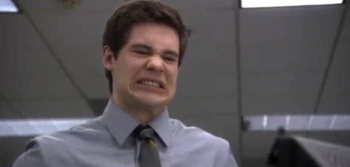Adam DeVine making a funny grimace in an office setting