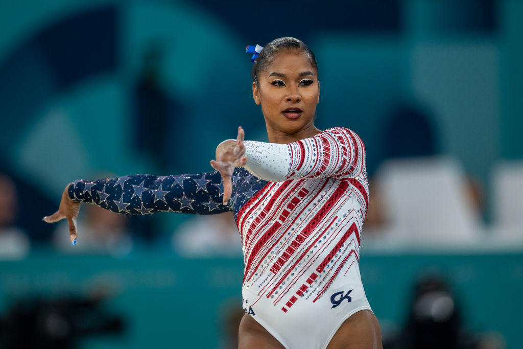 Gymnast performing routine, wearing a patriotic leotard with stars and stripes