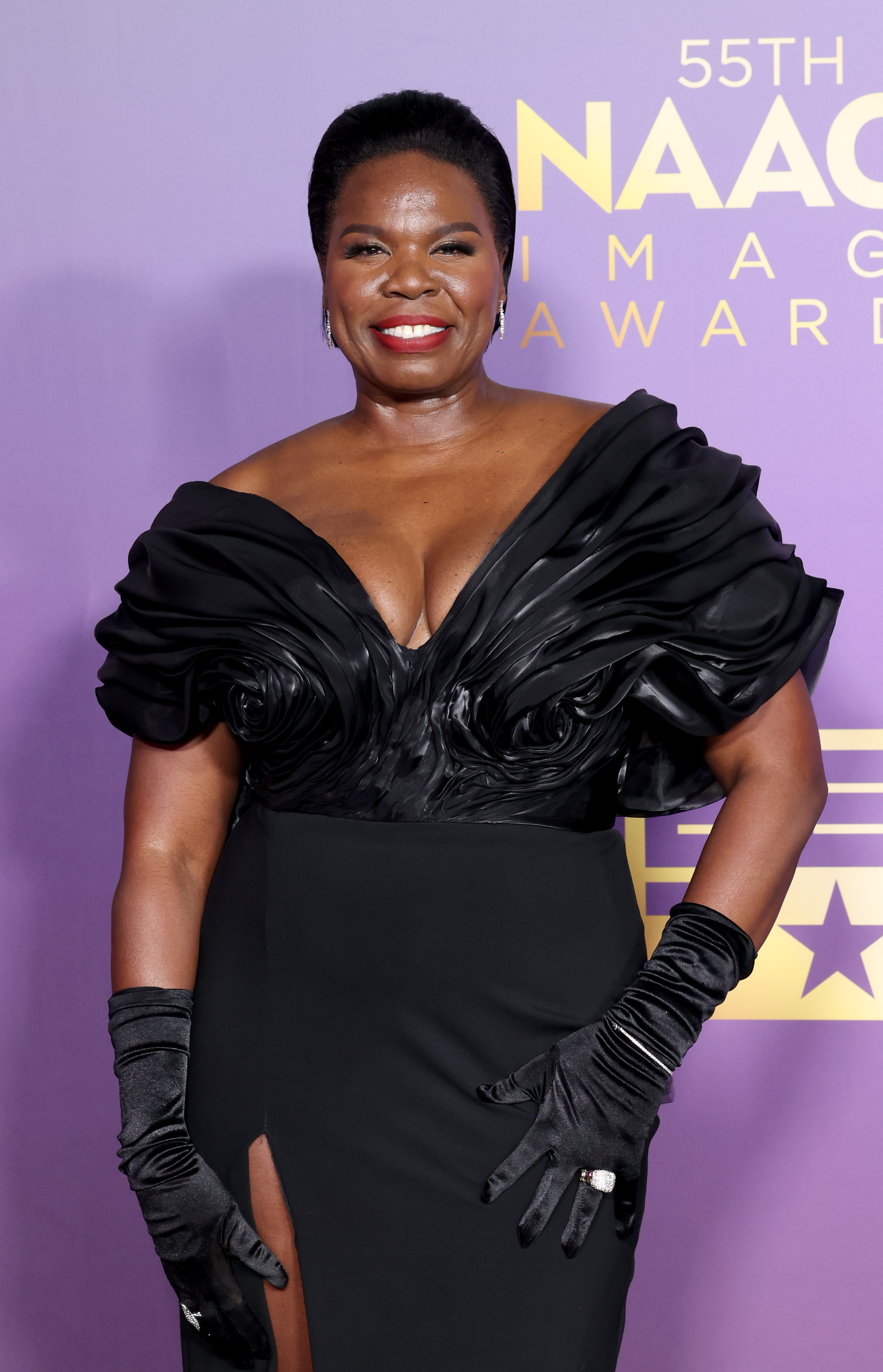 Leslie Jones at the 55th NAACP Image Awards, wearing an elegant black gown with intricate detailing and matching gloves