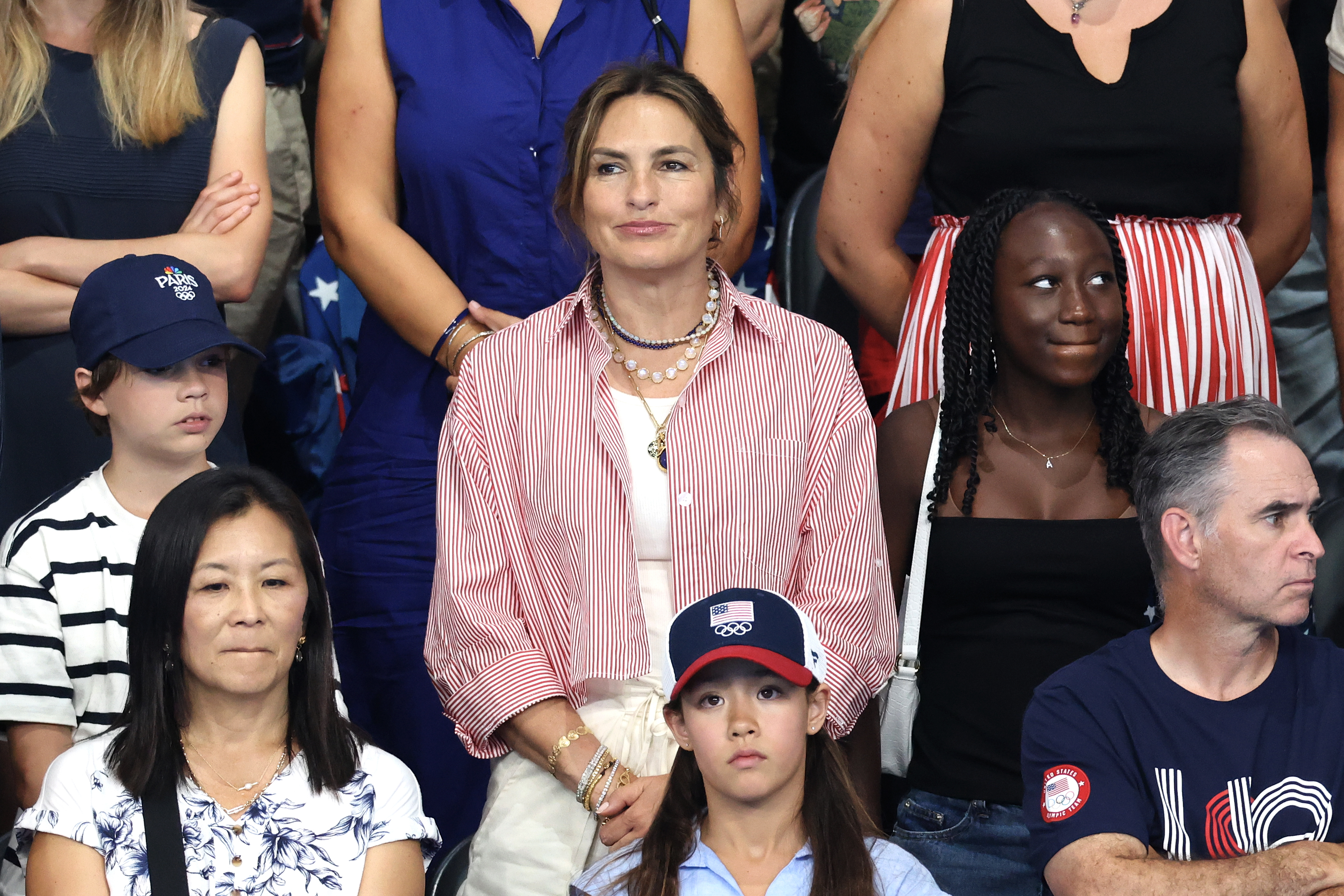 Mariska Hargitay at a public event, wearing a striped shirt and layered necklaces, surrounded by fans and attendees