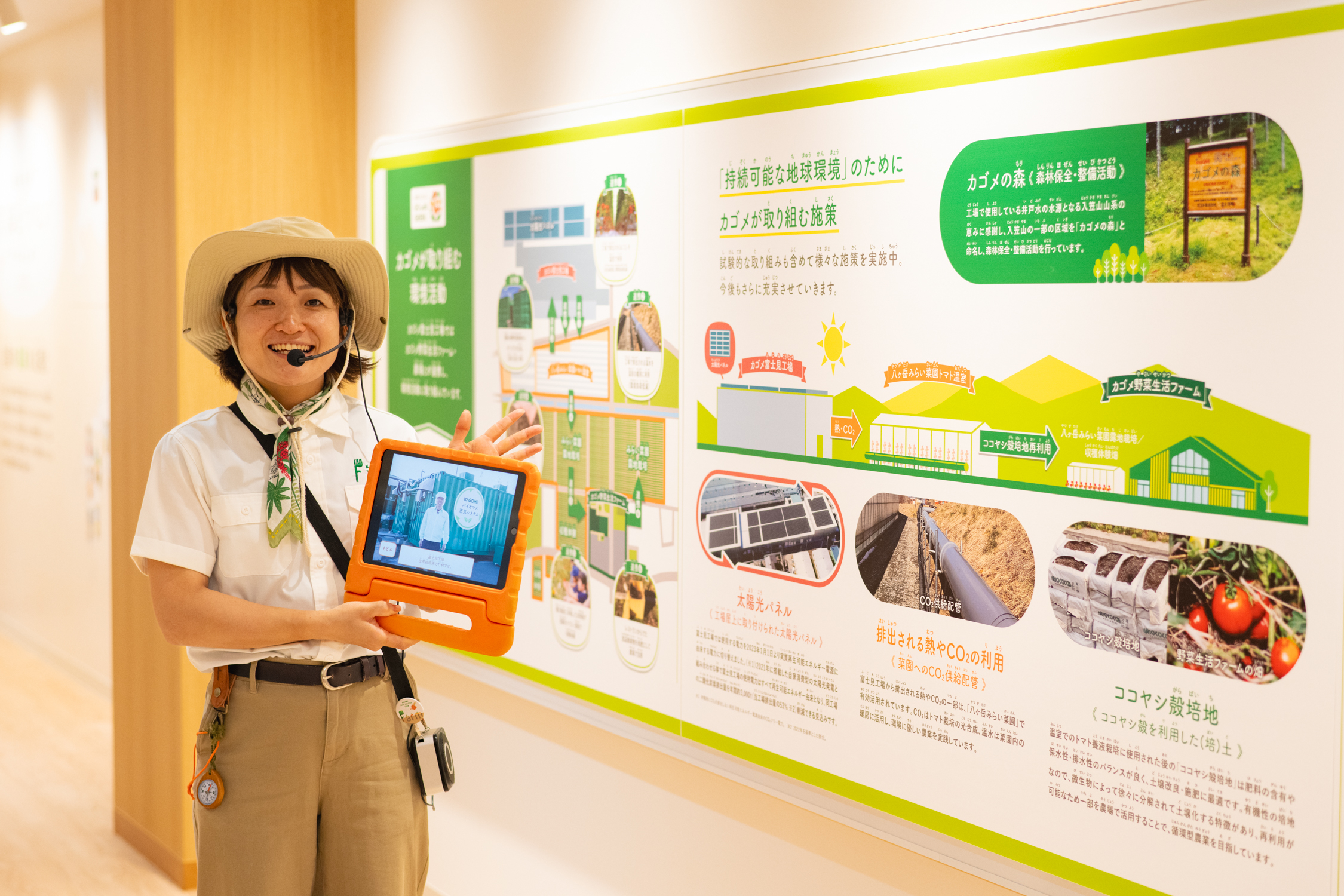 女性が展示パネルを指し、説明しています。説明パネルには環境や持続可能な農業についての情報が書かれています。