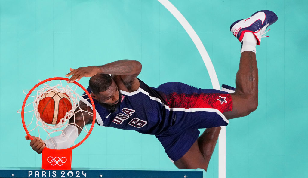 LeBron James, wearing a blue Team USA basketball uniform, performs a slam dunk during a game for the Paris 2024 Olympics