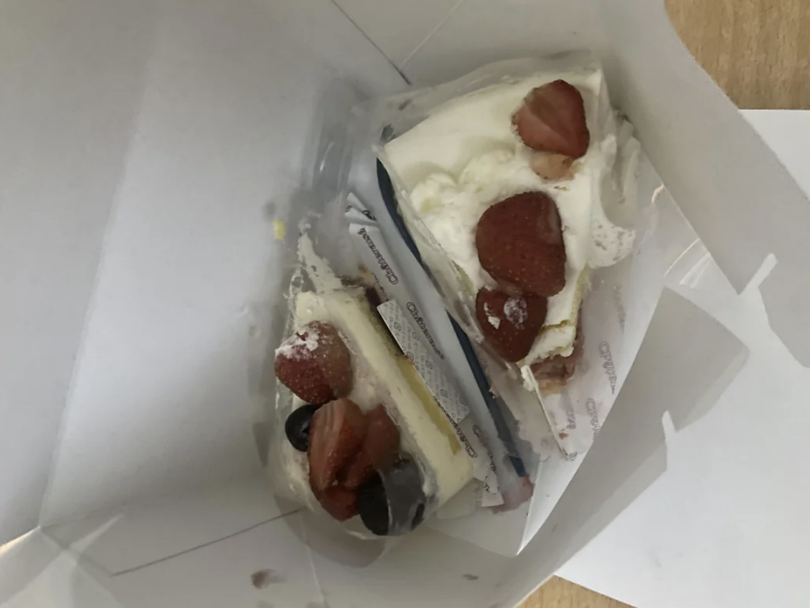 Two slices of cake in a box, each topped with whipped cream and fresh strawberries