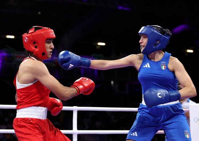 Salpicadura de imagen de dos boxeadoras olímpicas en el ring, una con uniforme rojo y otra con uniforme azul, durante un combate