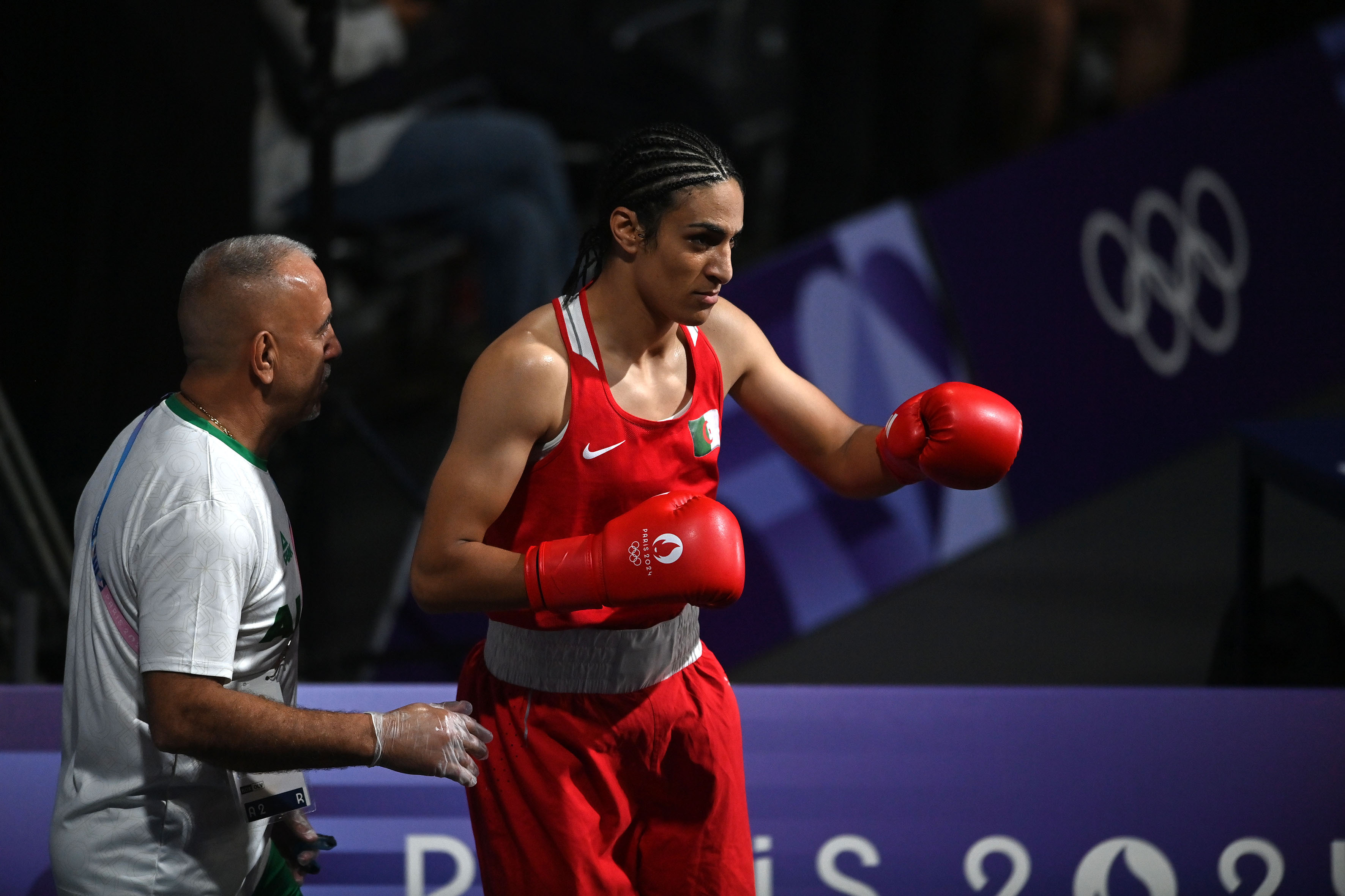 Boxeadora con uniforme rojo y guantes rojos se prepara para el combate junto a su entrenador en los Juegos Olímpicos París 2024