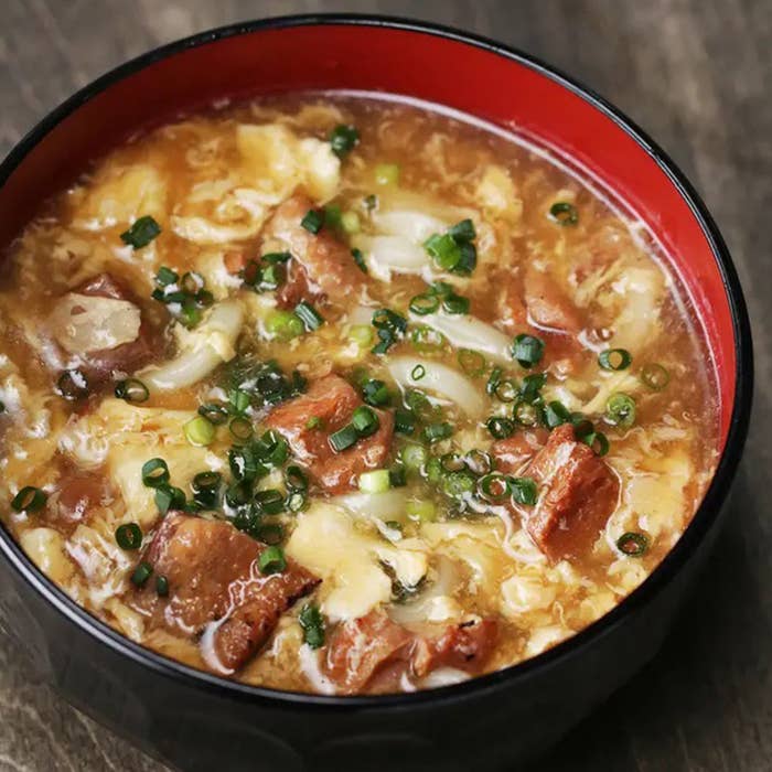 どんぶりに盛られた味噌汁。具材にネギ、豆腐、刻んだ野菜、肉が含まれています。