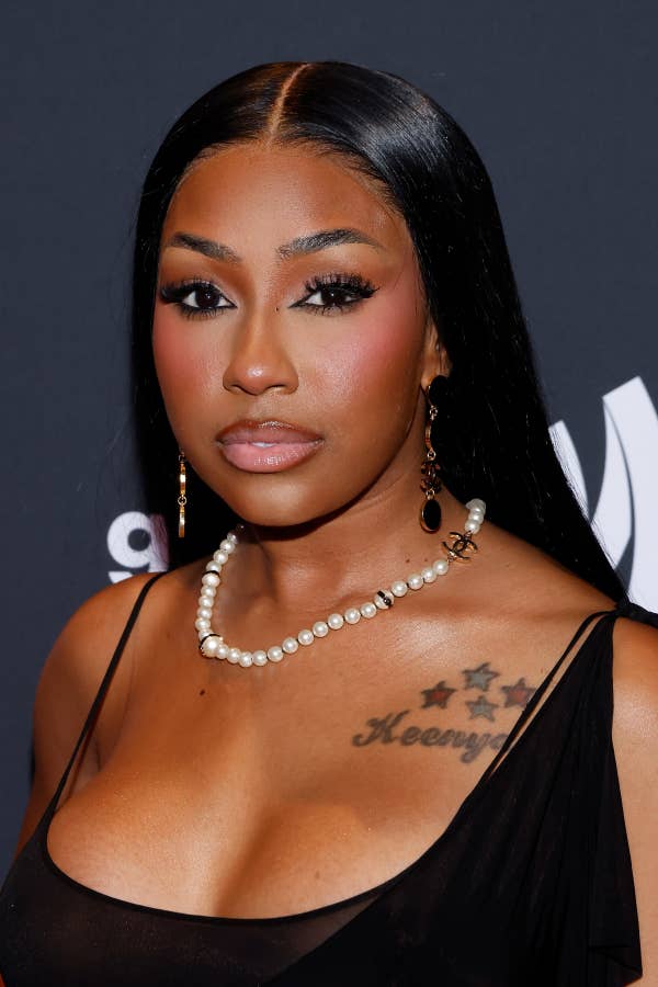 Yung Miami on the red carpet, wearing elegant jewelry and a stylish black dress, featuring a pearl necklace and earrings