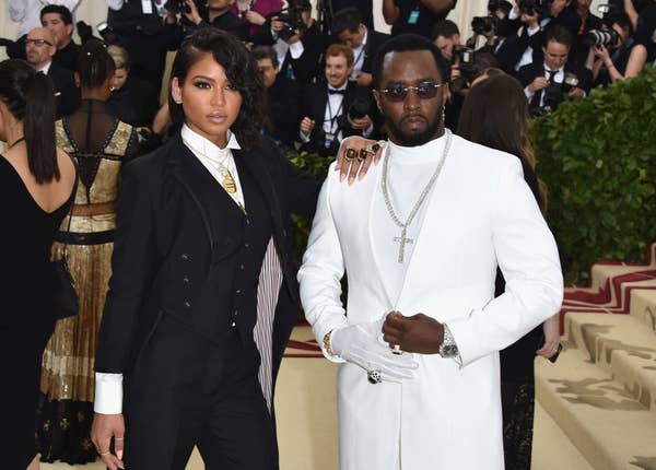 Cassie Ventura in a black suit stands next to Sean &quot;Diddy&quot; Combs in a white suit at a red carpet event
