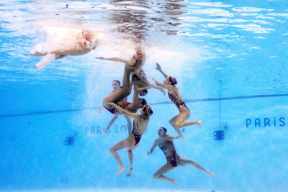 Synchronized swimmers perform an underwater routine during the Paris 2024 qualifiers