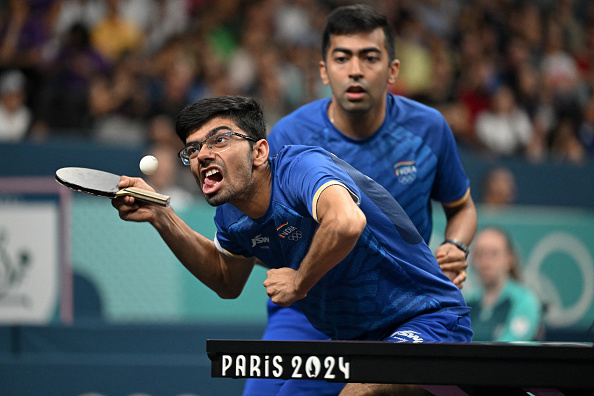 Sharath Kamal and Sathiyan Gnanasekaran intensely play table tennis at the Paris 2024 event. Sharath Kamal is focused on hitting the ball