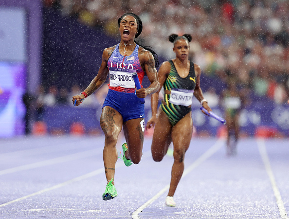 Sha'Carri Richardson (left) and Natasha Morrison (right) sprinting on a track during a race, with Richardson visibly celebrating as she crosses the finish line