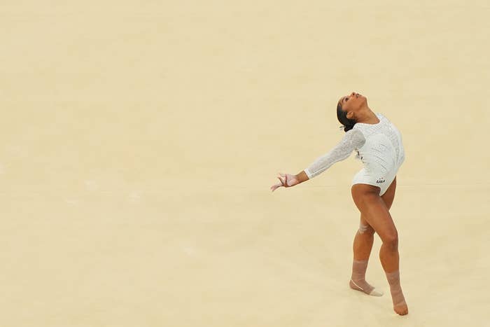 Jordan Chiles performs a graceful gymnastics routine on a light-colored floor, wearing a sparkly leotard