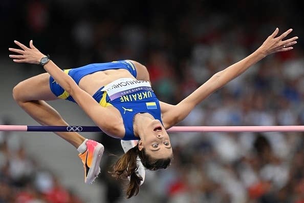 Ukraine's Yaroslava Mahuchikh performs a high jump at an athletic event, mid-air with her back arched over the bar and eyes focused upward
