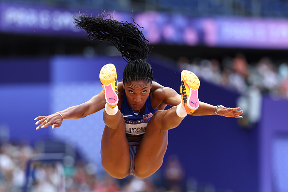A female athlete, Tshenolo Lemao, mid-air during long jump at a competition, focused and determined