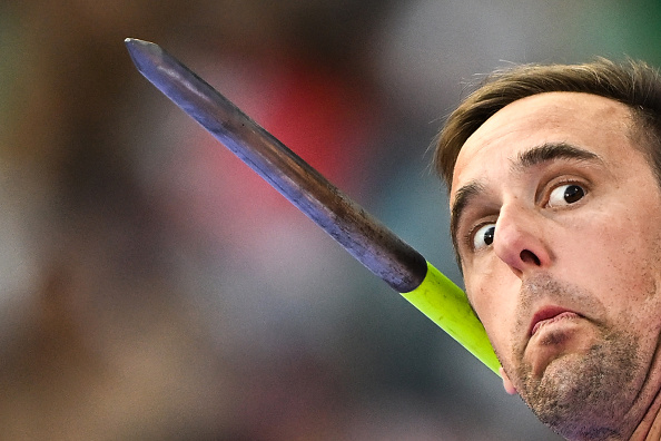 A man with a surprised expression poses with a javelin appearing to be dangerously close to his face