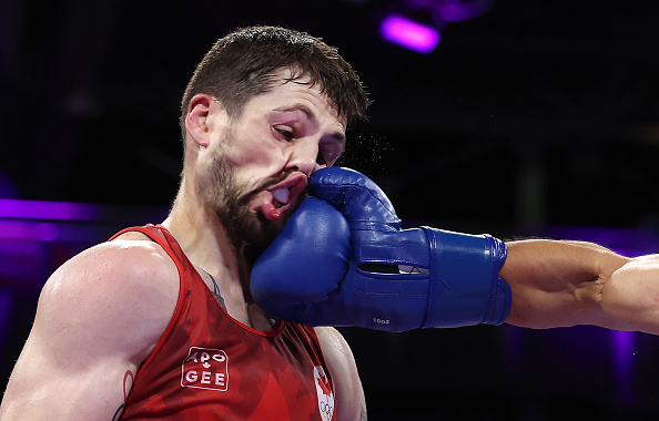 A boxer receives a powerful punch to the face from an opponent wearing blue gloves in a boxing match
