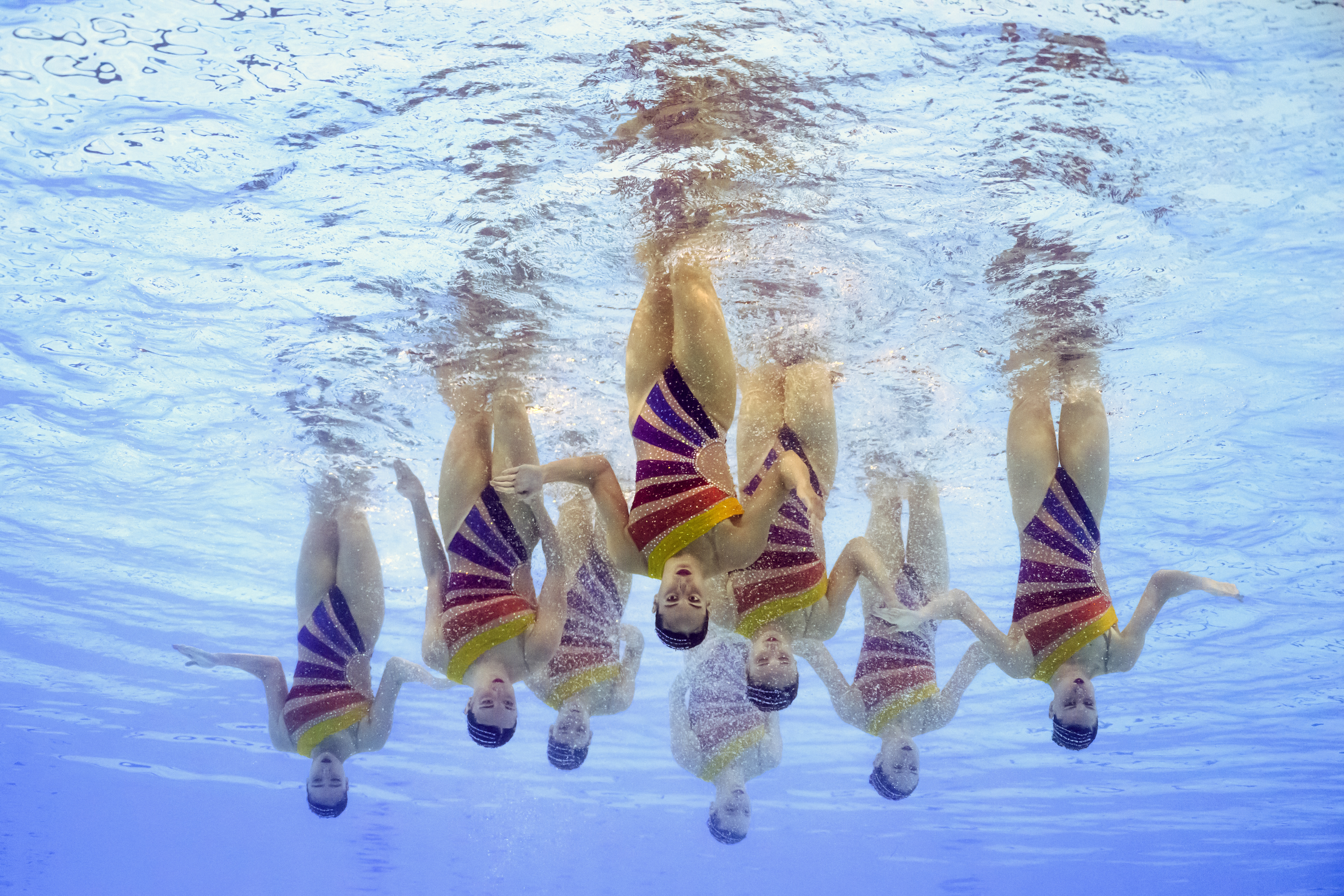 "Synchronized swimming team performing underwater."
