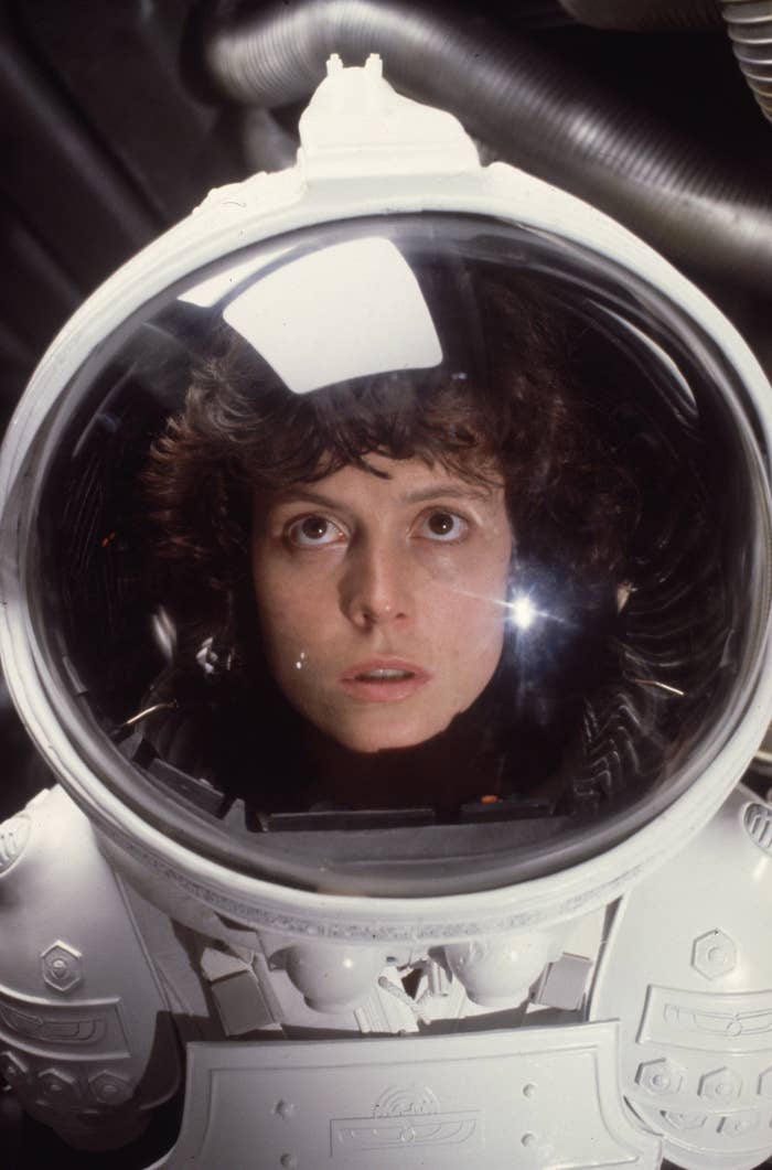 Sigourney Weaver in full astronaut suit, helmet on, staring intently. Robot-like elements and metallic texture create a futuristic atmosphere