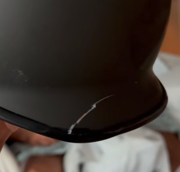 Close-up of a black equestrian helmet with a noticeable crack on the brim