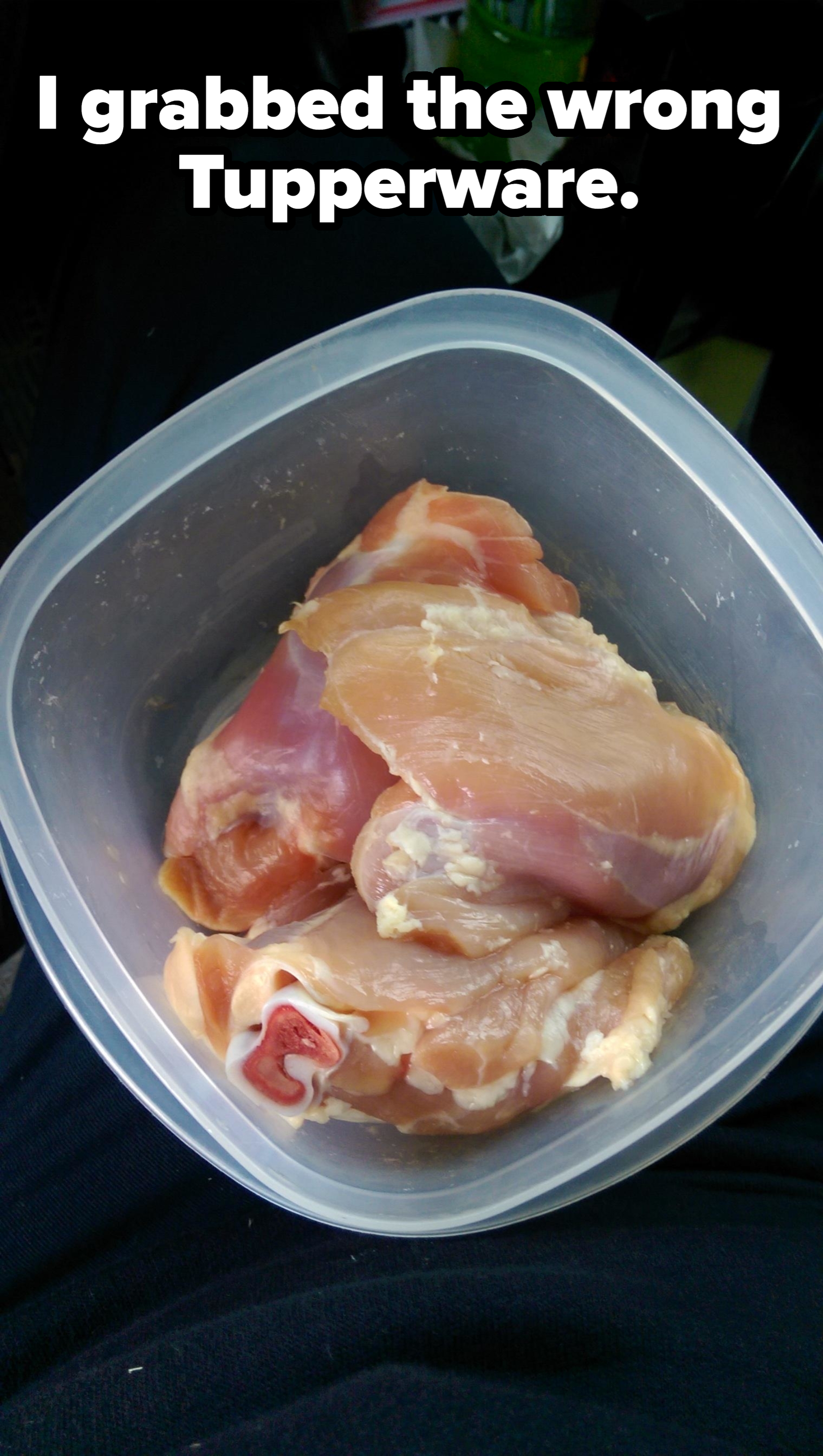 Raw chicken breasts in a plastic container, placed on a dark surface