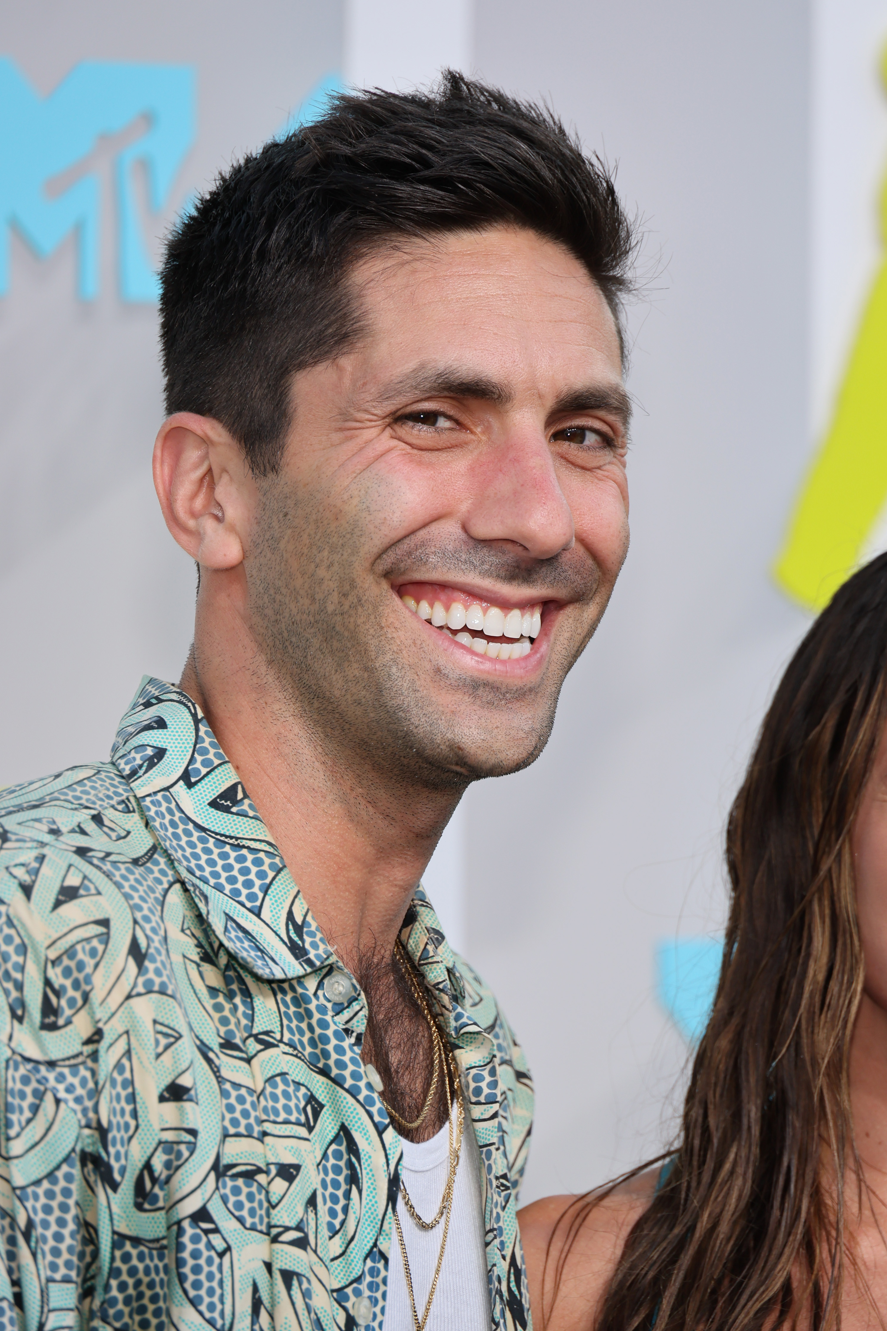 Nev Schulman smiling at an event, wearing a patterned shirt