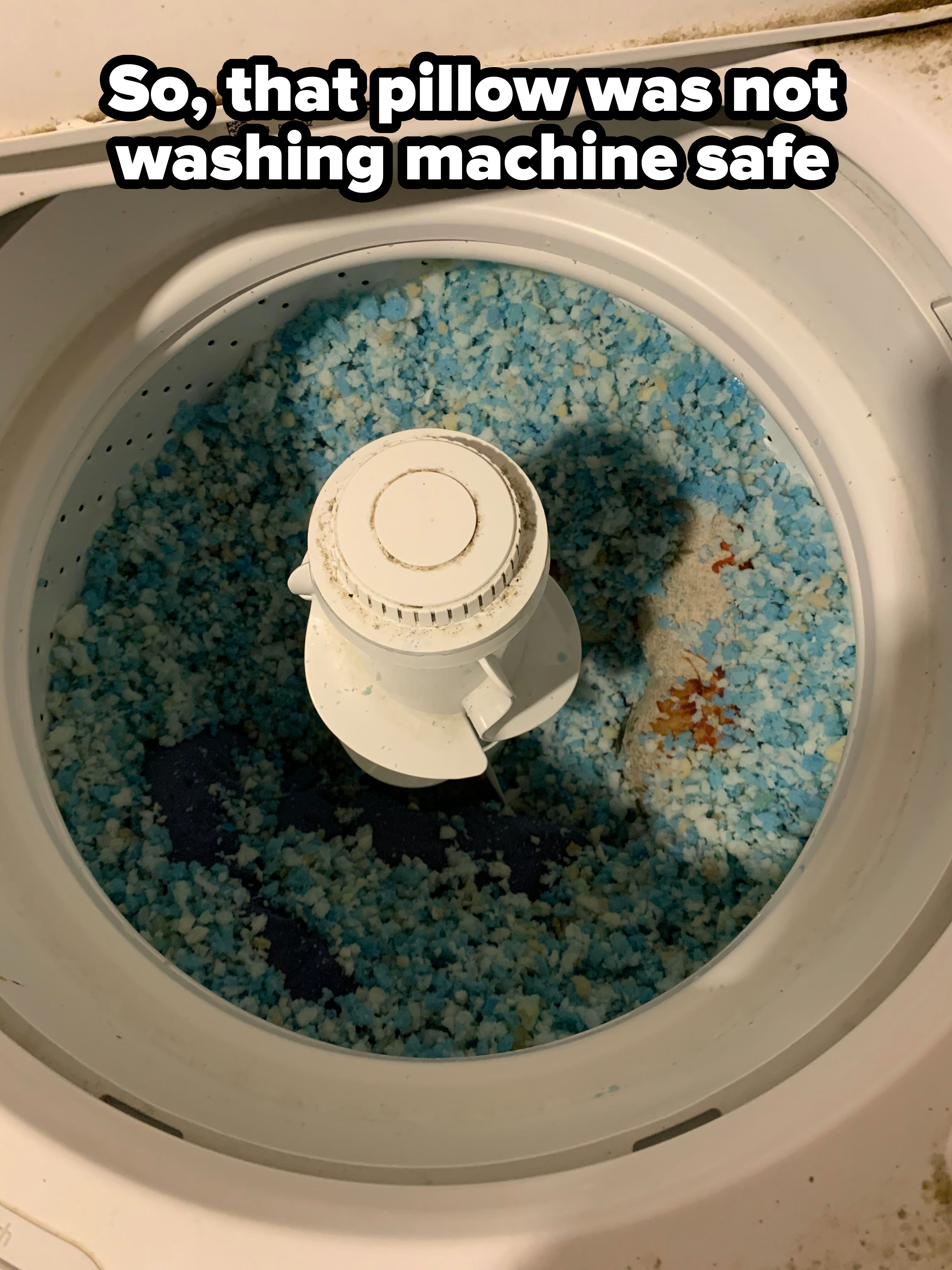 Open washing machine filled with blue detergent pod remnants and small laundry items